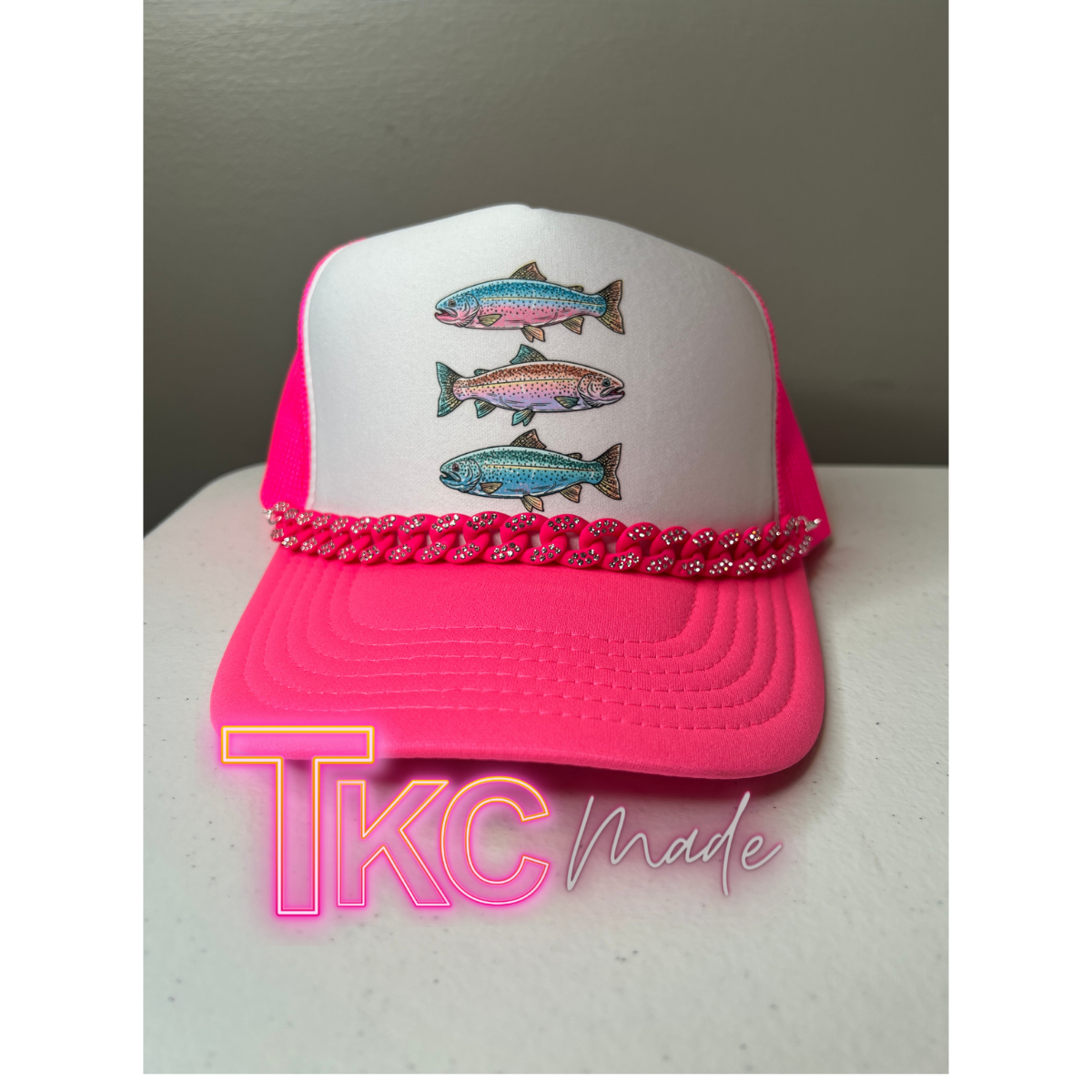 Pink and white cap with fish designs on a neutral background