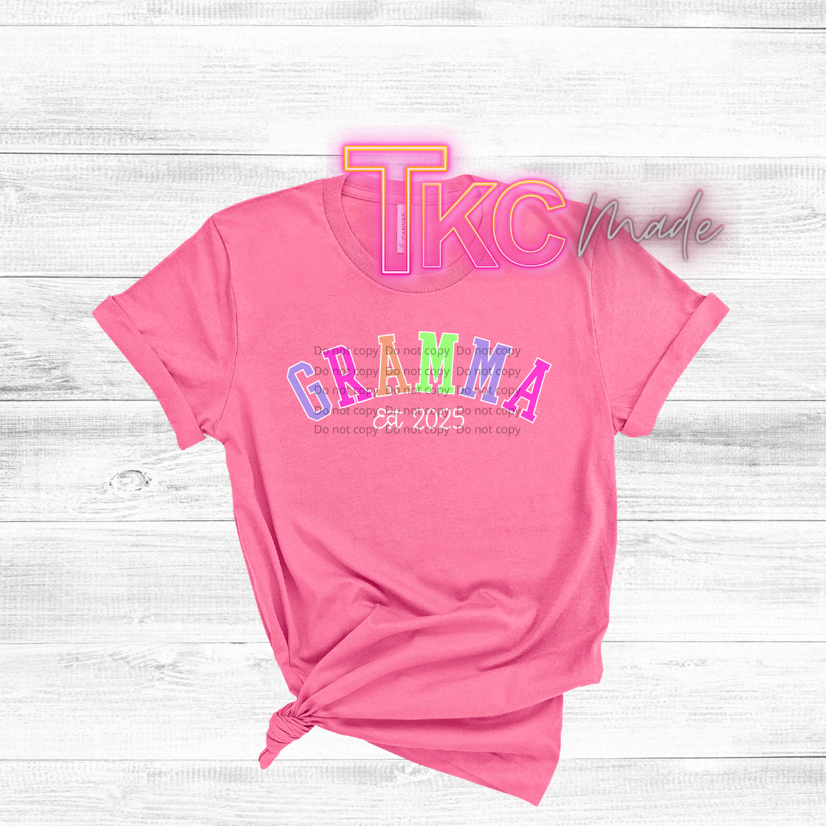 Pink t-shirt with colorful text  gramma on a light wooden surface