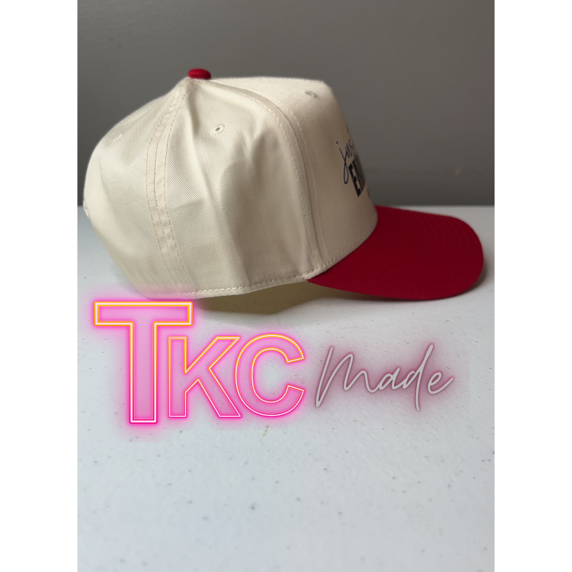 Beige and red cap on a light gray surface with 'TKC made' text in neon pink and white.