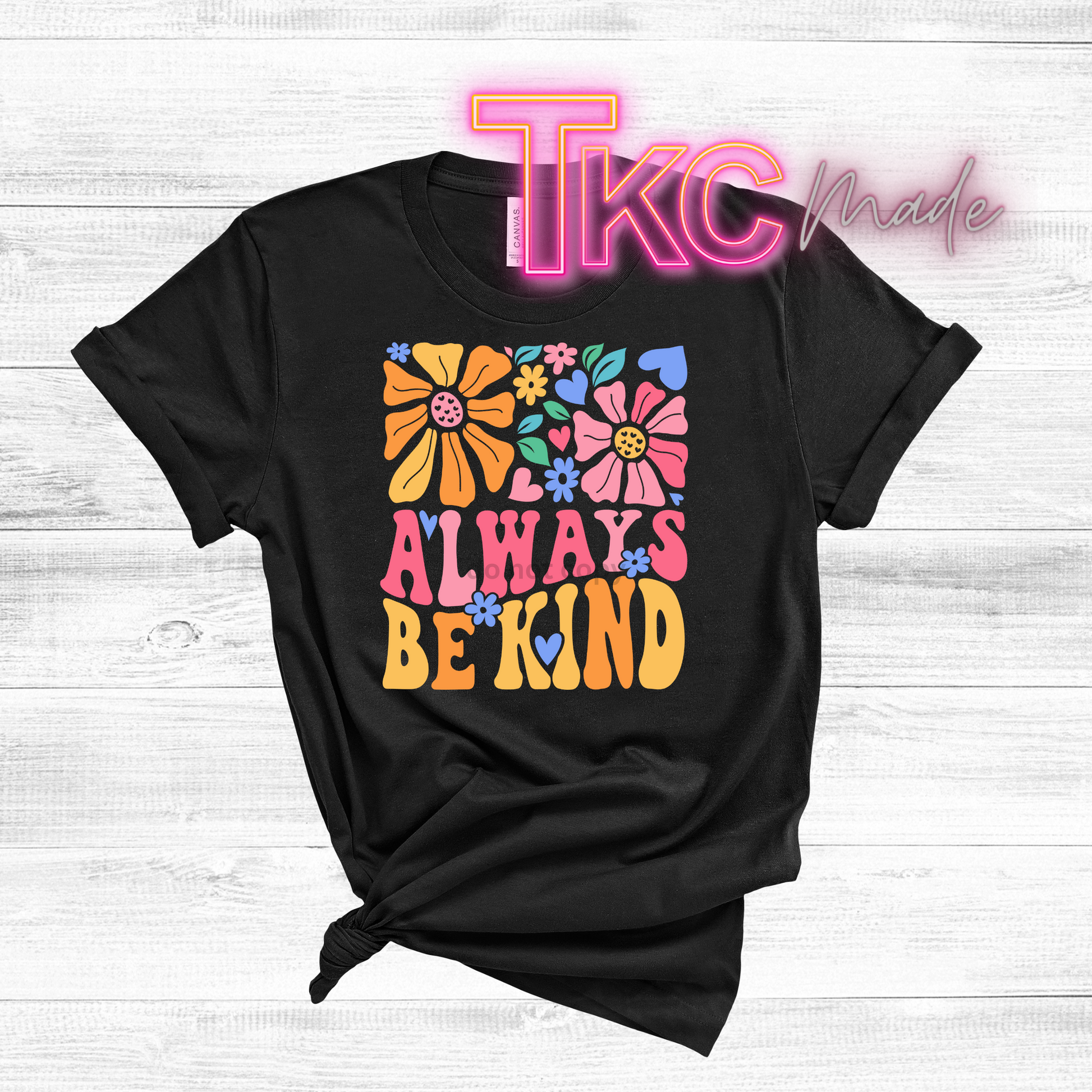 Black t-shirt with colorful floral design and text on a light wooden background