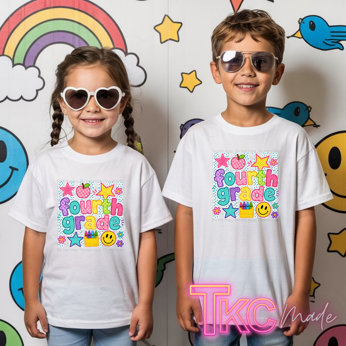 Two children wearing matching white graphic T-shirts with a colorful 'fourth grade' design, standing in front of a decorated wall with cartoon smiley faces, stars, and a rainbow. The child on the right wears sunglasses, and there is a 'TKC Made' watermark at the bottom right.