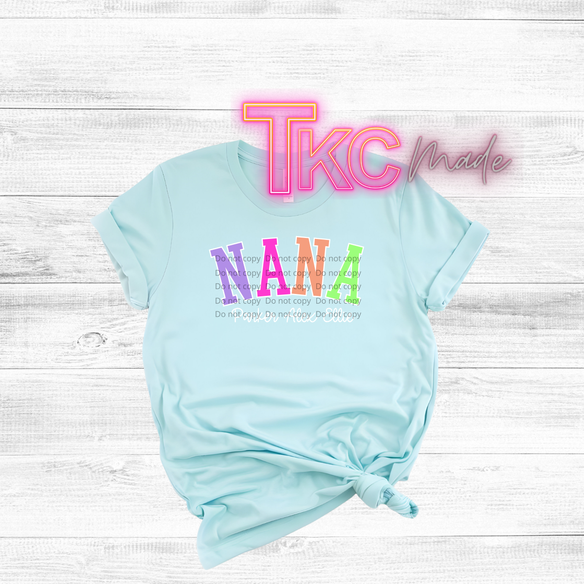 Light blue t-shirt with colorful text on a white wooden background