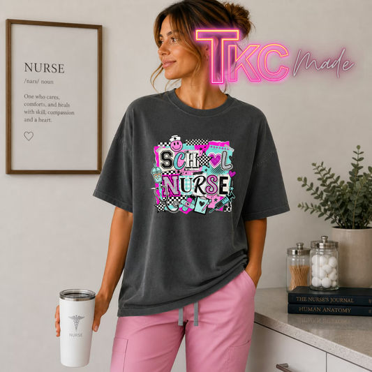 A woman wearing a dark gray graphic t-shirt that reads 'SCHOOL NURSE' in a colorful collage style, paired with pink pants, holding a white travel tumbler. The background is a clean, modern room with a framed print on the wall and a plant on a counter.