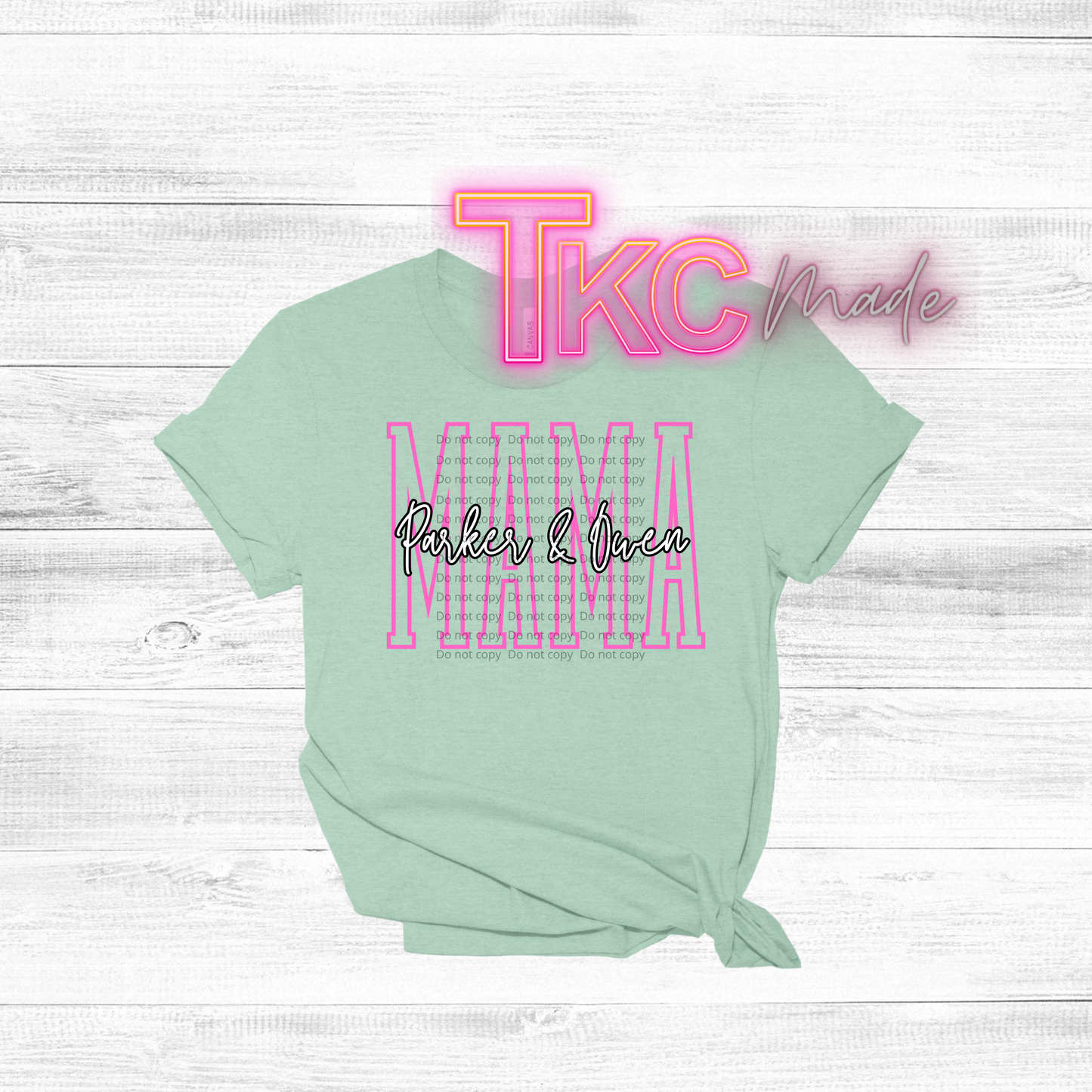 Mint green t-shirt with pink and black text on a white wooden background