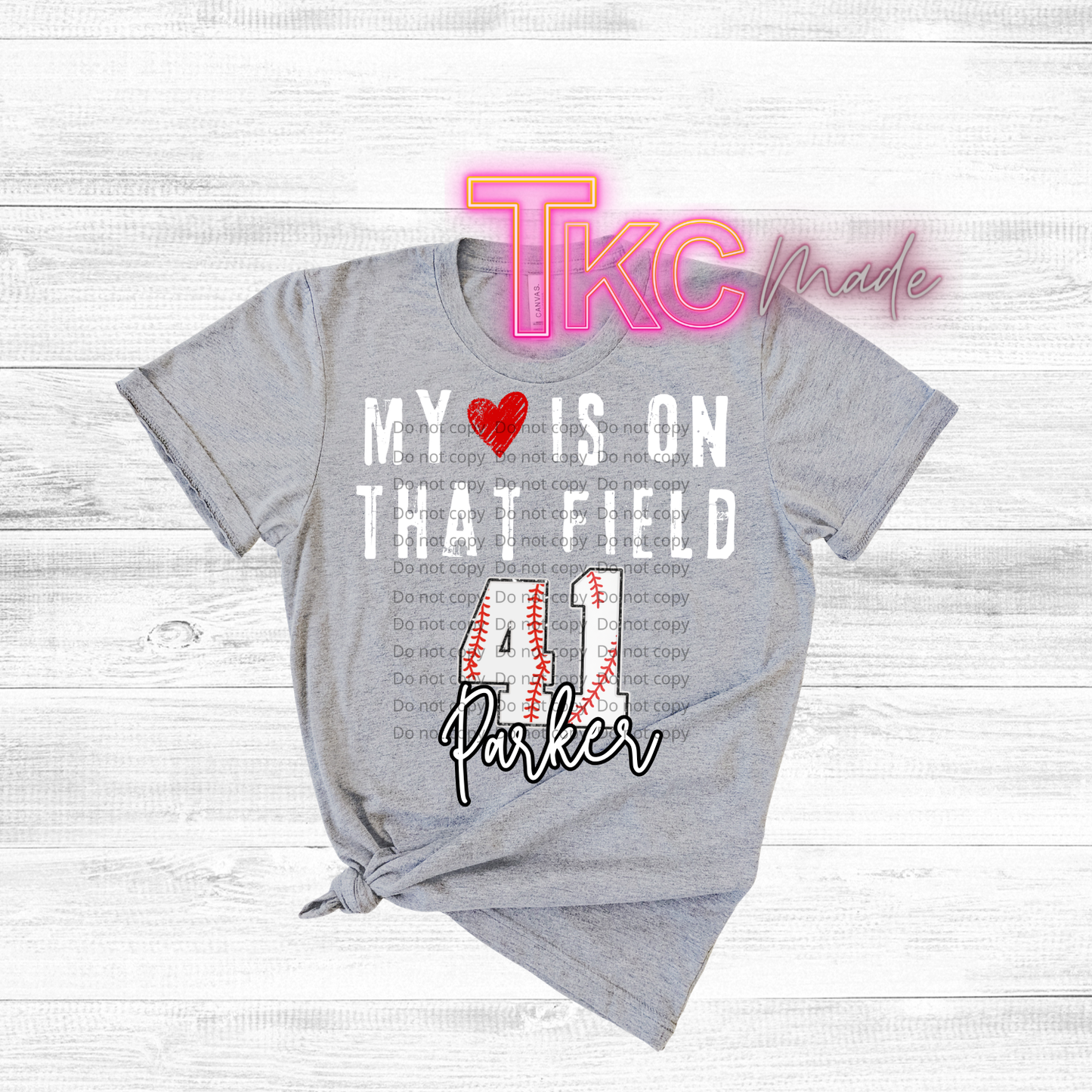 Gray t-shirt with baseball text-my heart is on that field with custom name and baseball number on a wooden surface