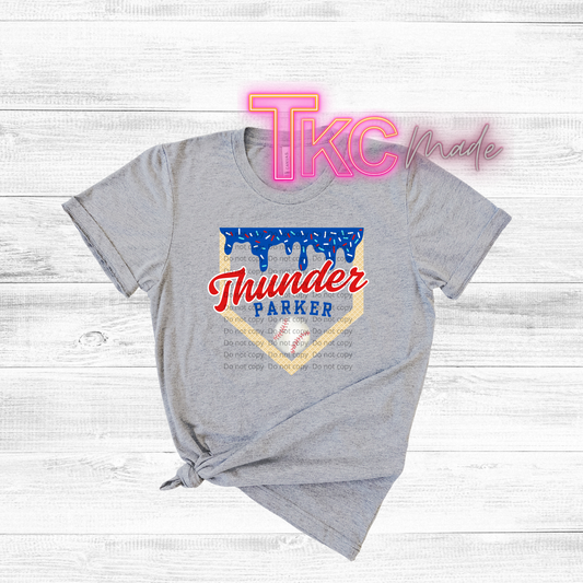 Gray t-shirt with 'Thunder Parker' design on a light wooden surface, featuring 'TKC made' text.