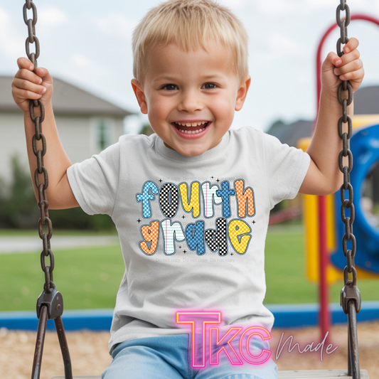 A young smiling boy sitting on a playground swing wearing a white t-shirt with a colorful 'fourth grade' graphic. The text features a mix of pastel blue, orange, yellow, and black-and-white checkered patterns.