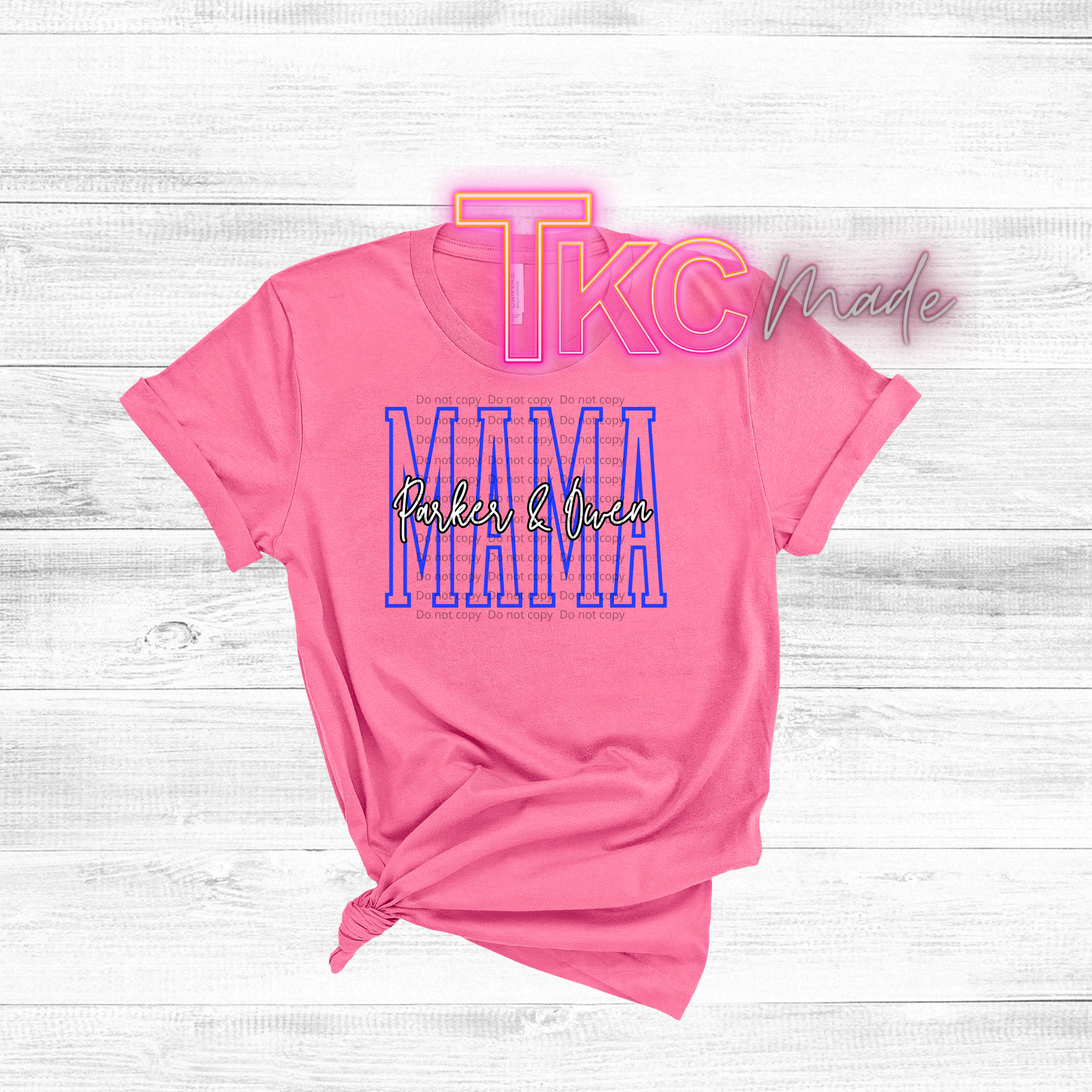 Pink t-shirt with 'TLC Made' and 'Mama' text on a light wooden surface