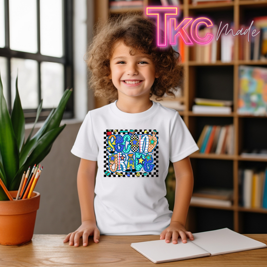 A smiling young girl with curly brown hair sits at a wooden desk wearing a white t-shirt with a colorful 'second grade' graphic. The background shows a cozy room with a bookshelf and a potted plant, and a pink 'Tkc Made' watermark is visible in the top right corner.