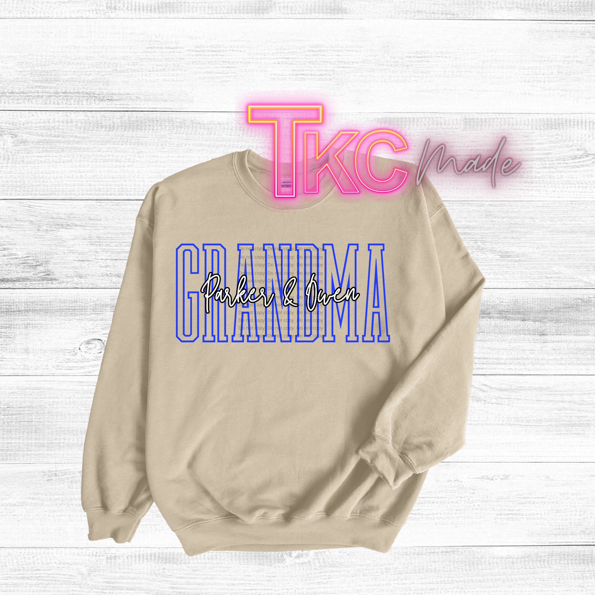 Beige sweatshirt with 'GRANDMA' text on a light wooden background