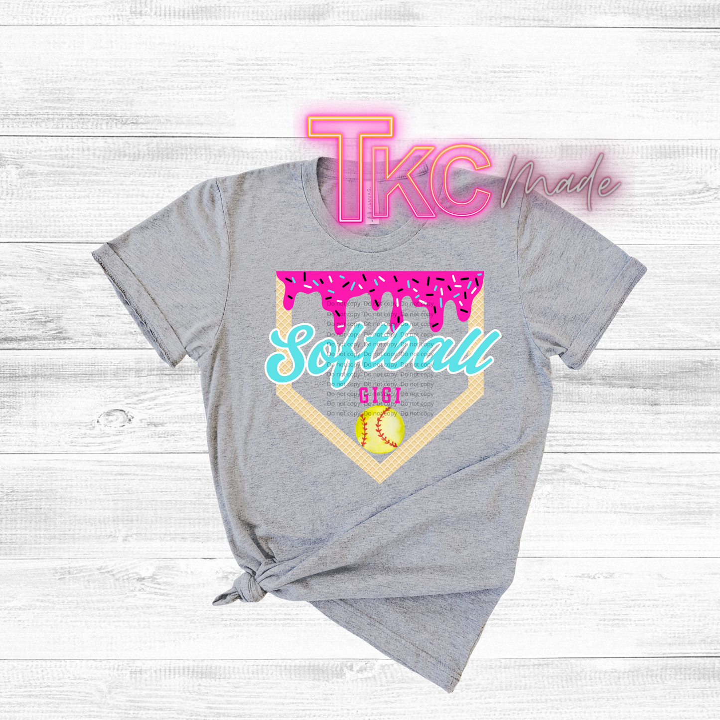 Gray t-shirt with 'TKC made' text and 'Softball Gigi' design on a wooden surface