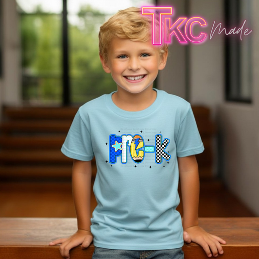 A young boy smiling and wearing a light blue t-shirt with a custom 'Pre-K' graphic on the chest, posed in front of a blurred indoor background. A pink 'Tkc Made' watermark is visible in the top right corner.