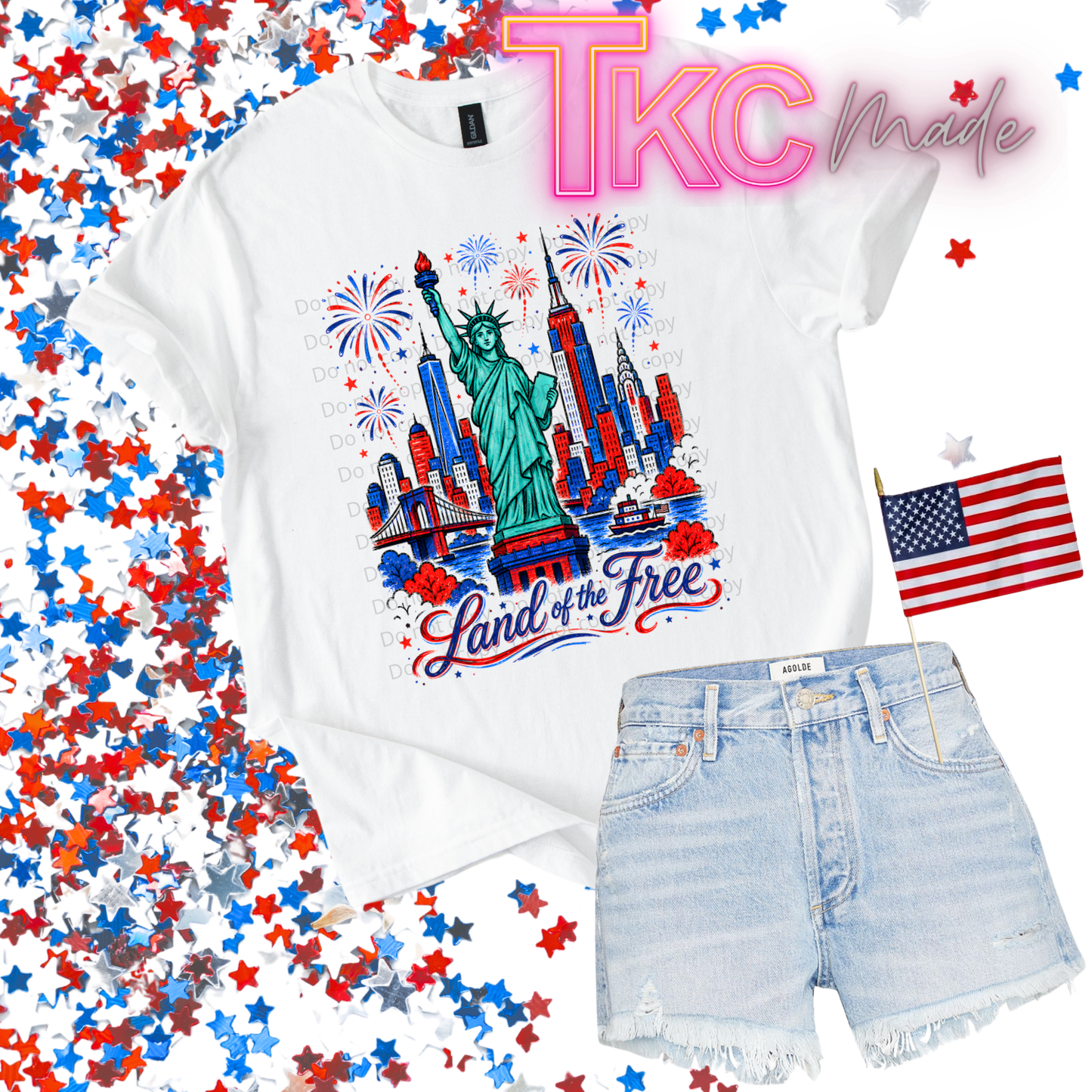 White t-shirt with Statue of Liberty and fireworks design, denim shorts, and American flag on a colorful confetti background.