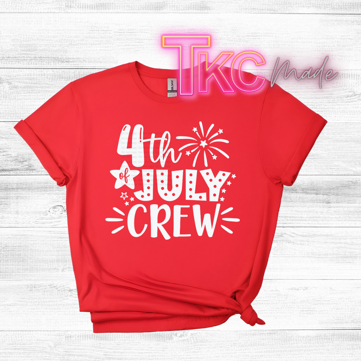 Red t-shirt with '4th of July Crew' text on a wooden surface, featuring the brand 'TKC Made'.