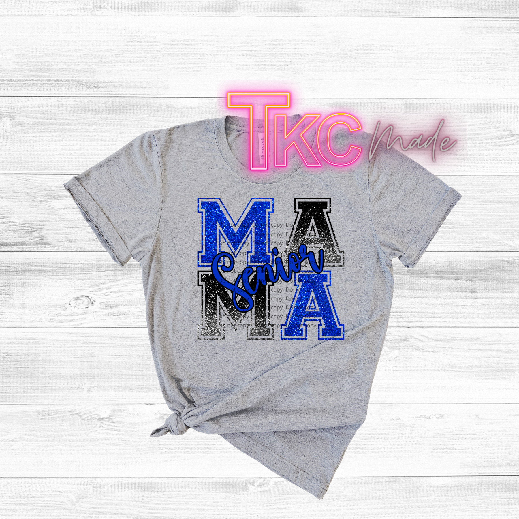 Gray t-shirt with 'MAMA Senior' text on a wooden surface, featuring 'TKC Made' branding.