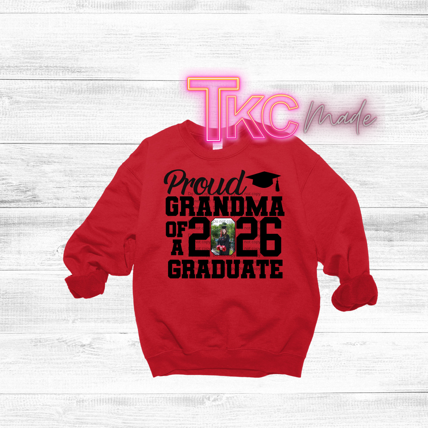 Red sweatshirt with text 'Proud Grandma of 2026 Graduate' on a white wooden background