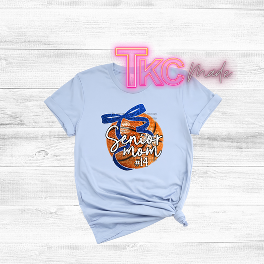 Light blue t-shirt with 'Senior Mom' design on a wooden surface, featuring 'TKC made' branding.