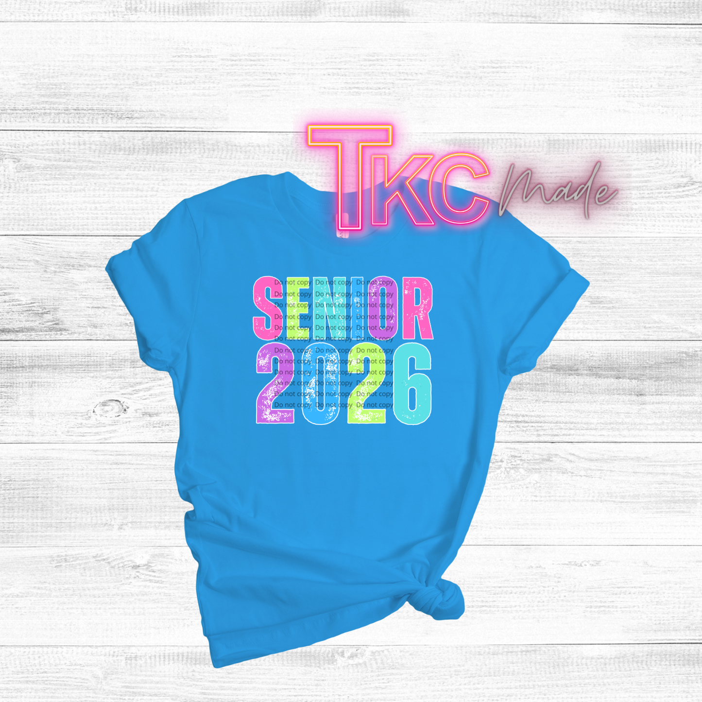 Blue t-shirt with 'Senior 2026' text on a light wooden surface