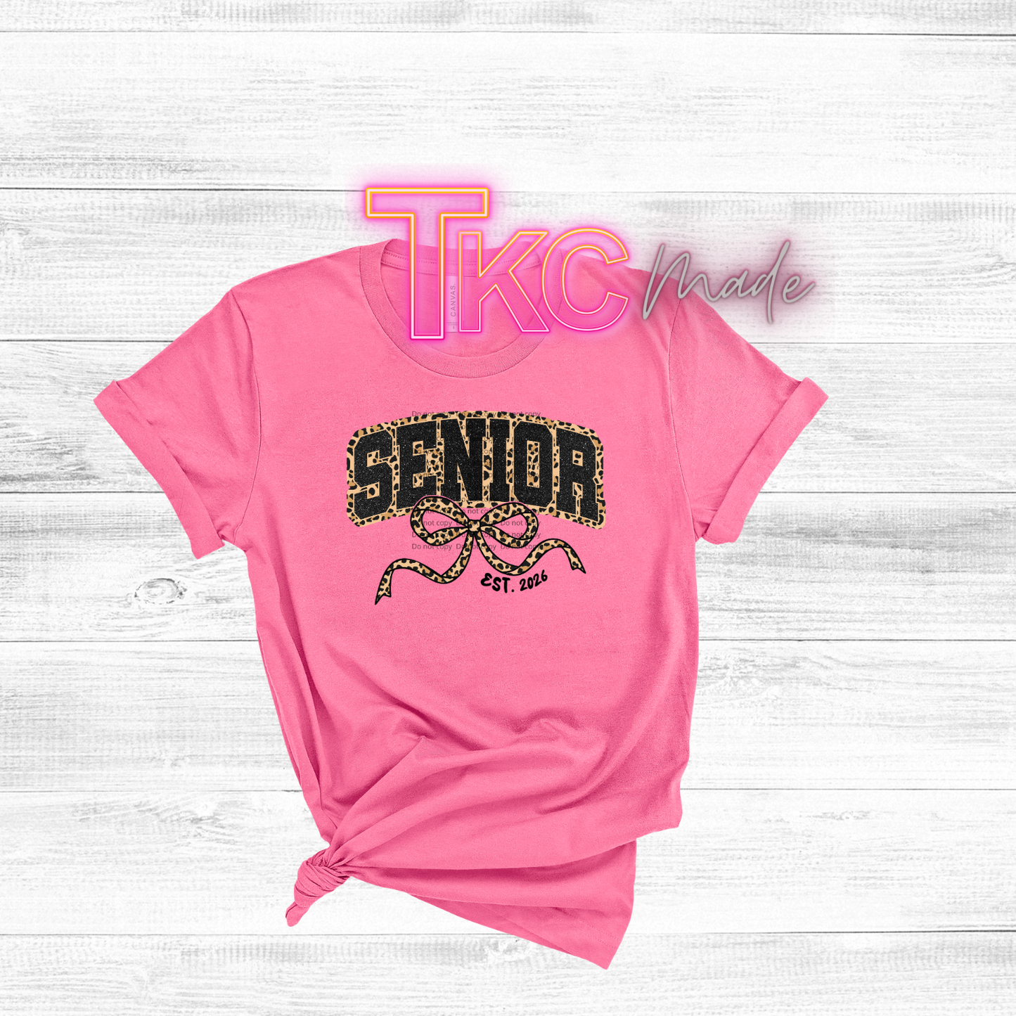 Pink t-shirt with 'SENIOR' and 'TKC Made' text on a white wooden background