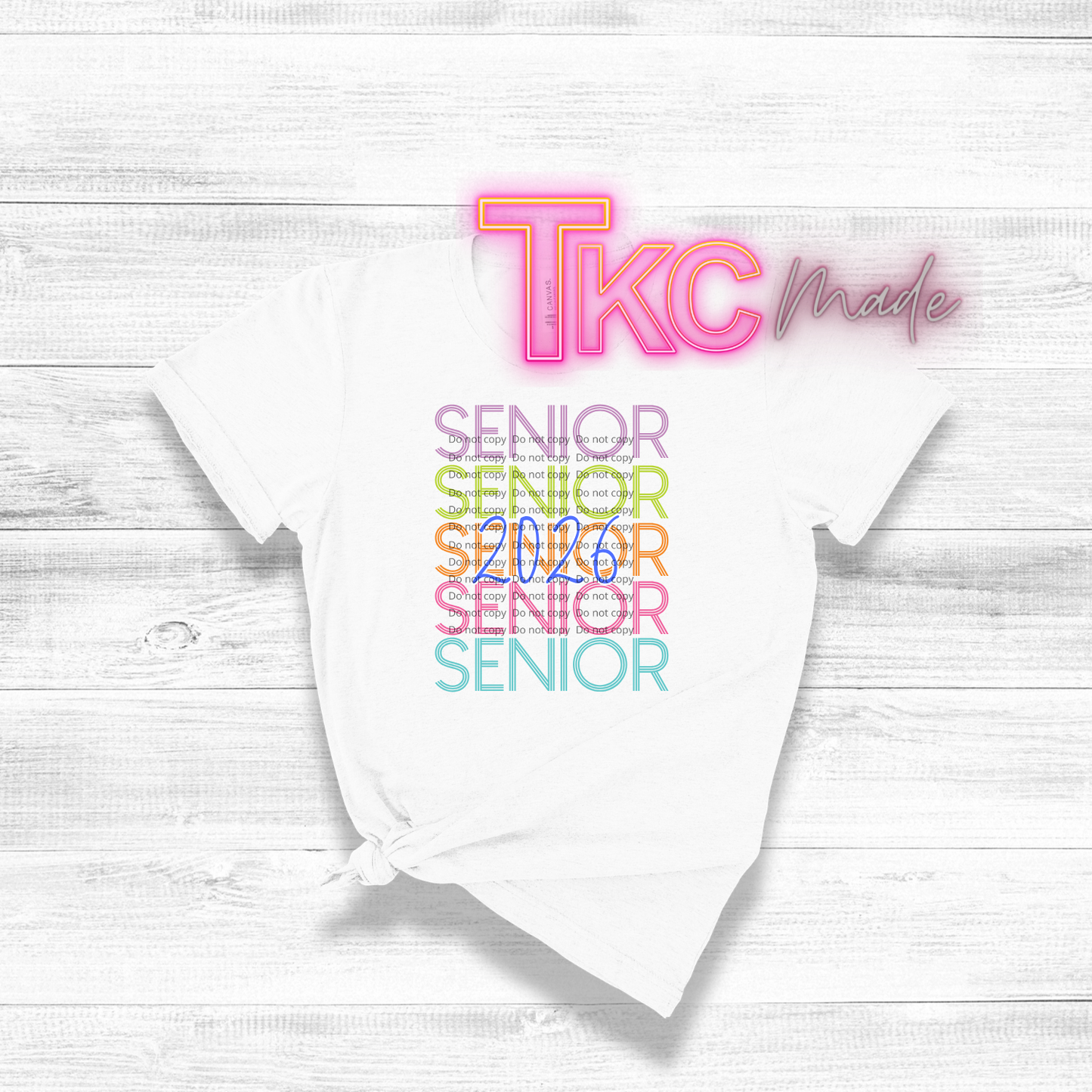 White t-shirt with 'TKC made' and 'Senior 2026' text on a light wooden surface