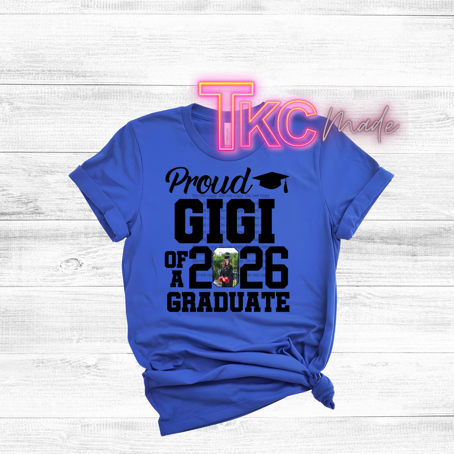 Blue t-shirt with 'Proud GIGI of a 2026 Graduate' text on a white wooden background