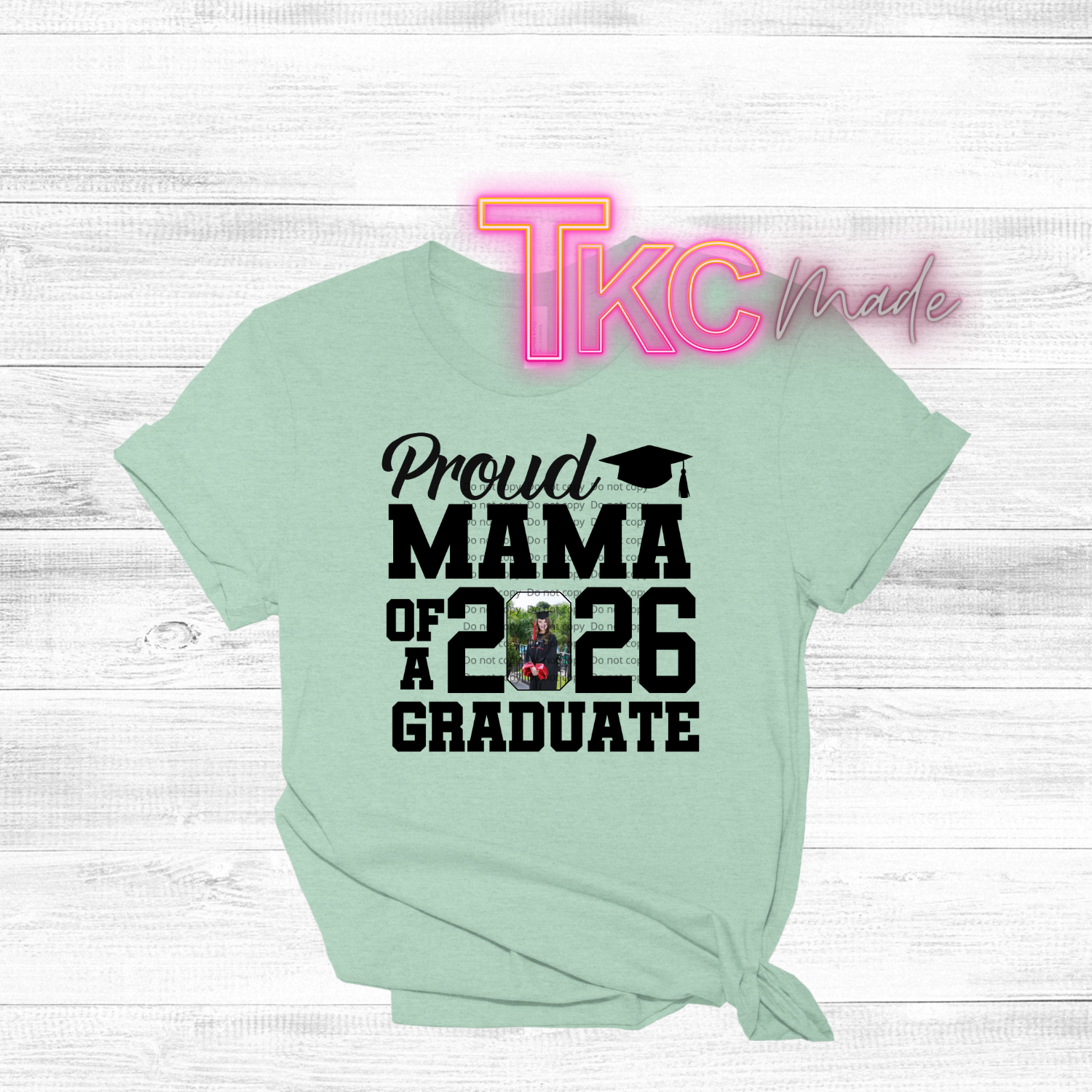 Mint green t-shirt with 'Proud Mama of a 2026 Graduate' text on a white wooden background