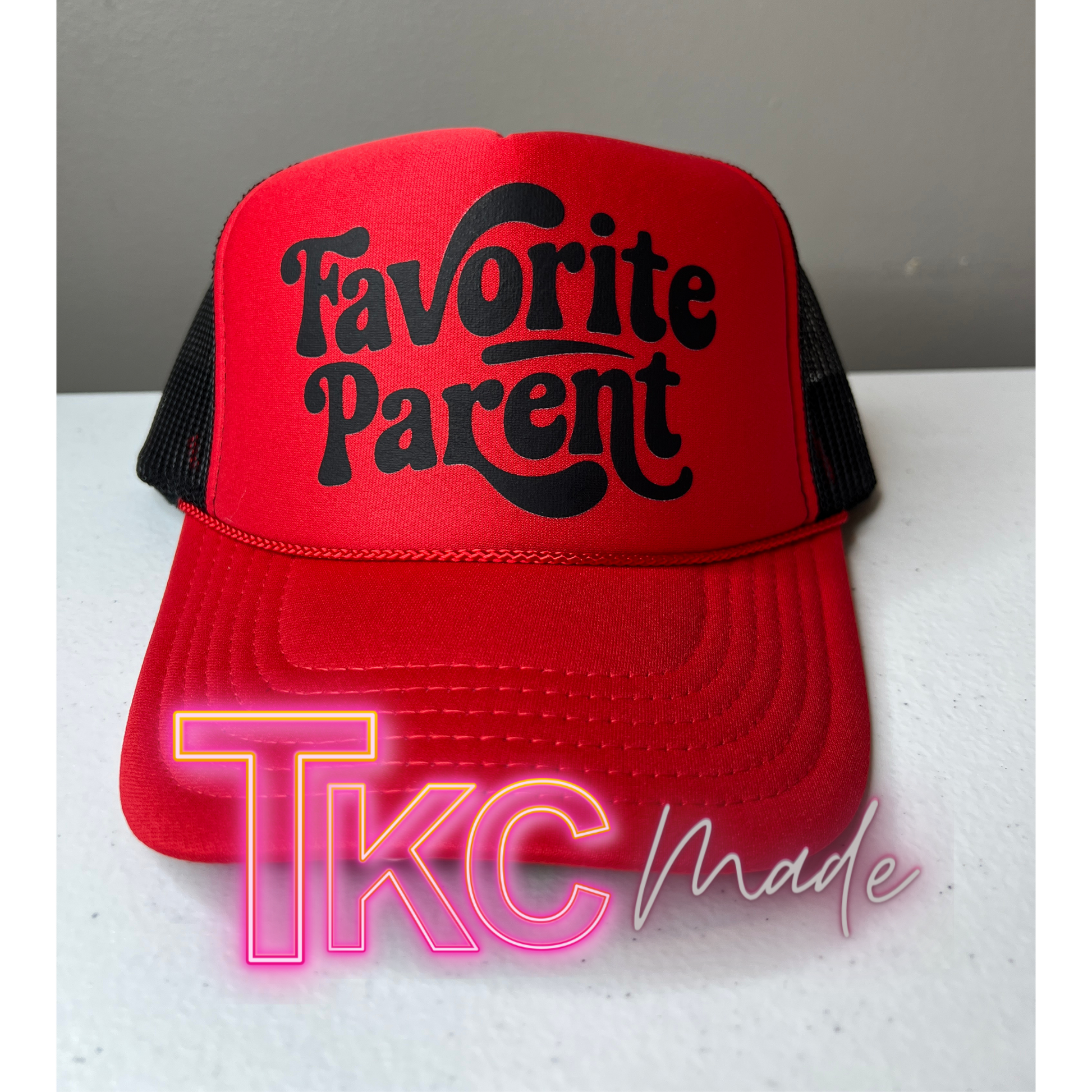 Red cap with 'Favorite Parent' text on a white surface, featuring 'TKC Made' branding.