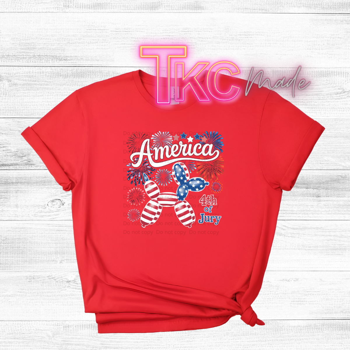 Red t-shirt with 4th of July design on a wooden surface, featuring the brand 'TKC Made'.
