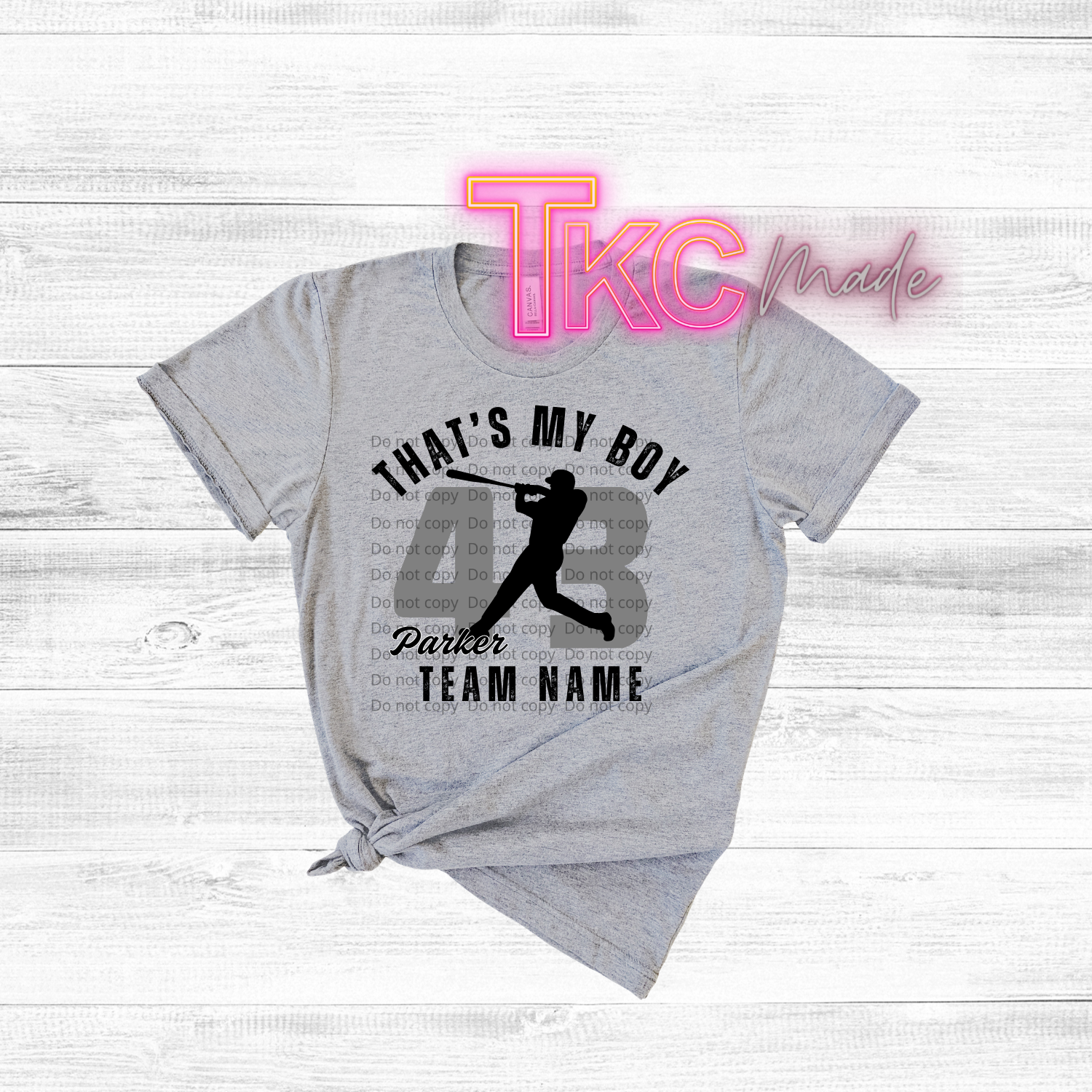 Gray t-shirt with sports-themed design and 'TKC made' branding on a light wooden background