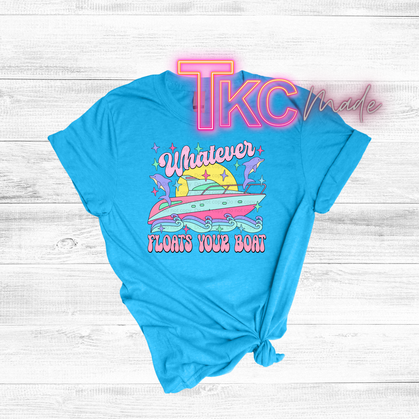 Blue t-shirt with colorful graphic design and 'TKC made' text on a light wooden background