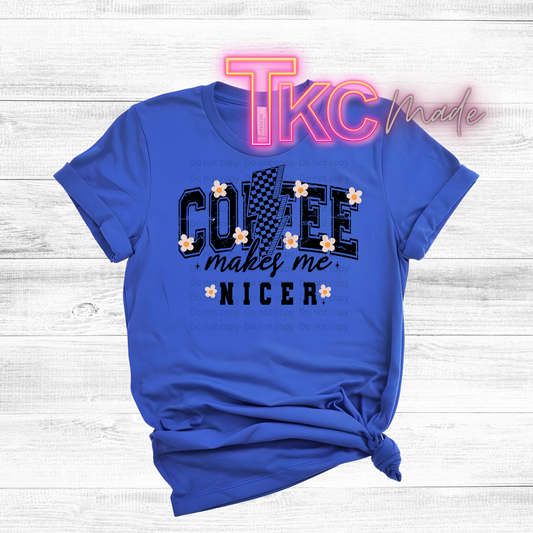 Blue t-shirt with 'Coffee makes me nicer' text on a wooden surface, featuring 'TKC made' branding.