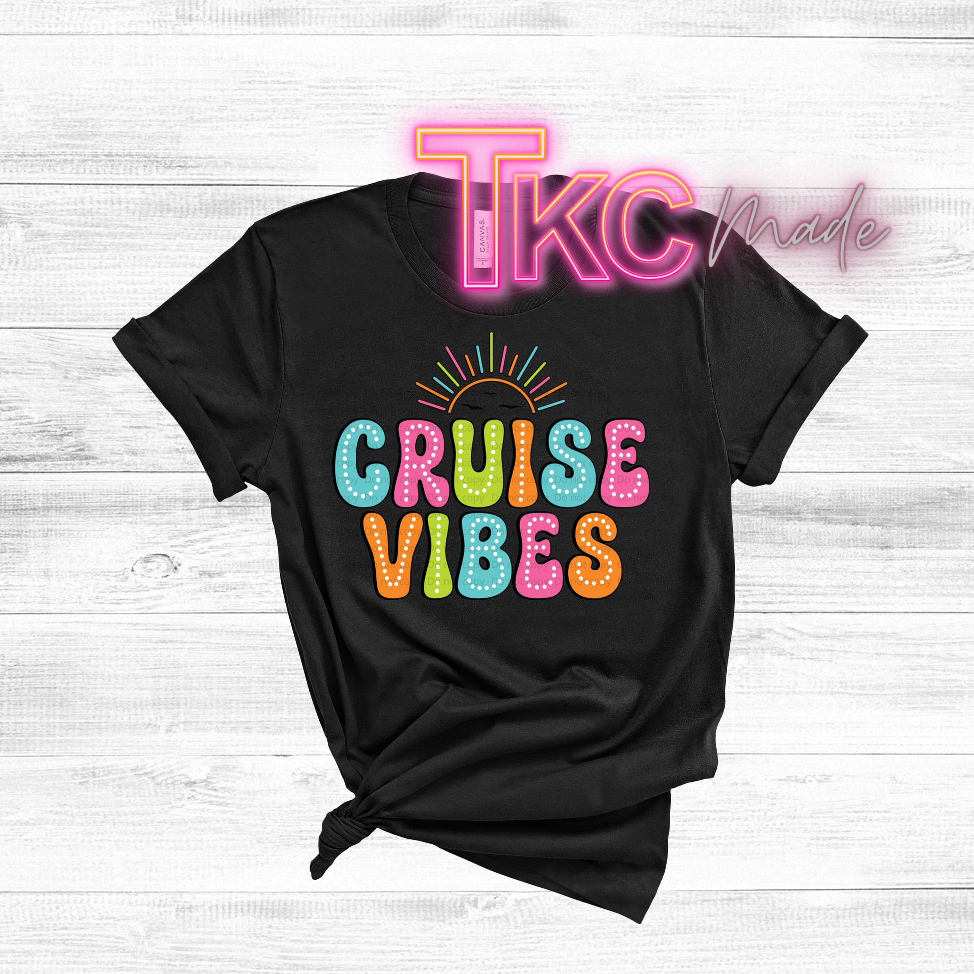 Black t-shirt with 'Cruise Vibes' text in colorful letters on a white wooden background with 'TKC Made' text.
