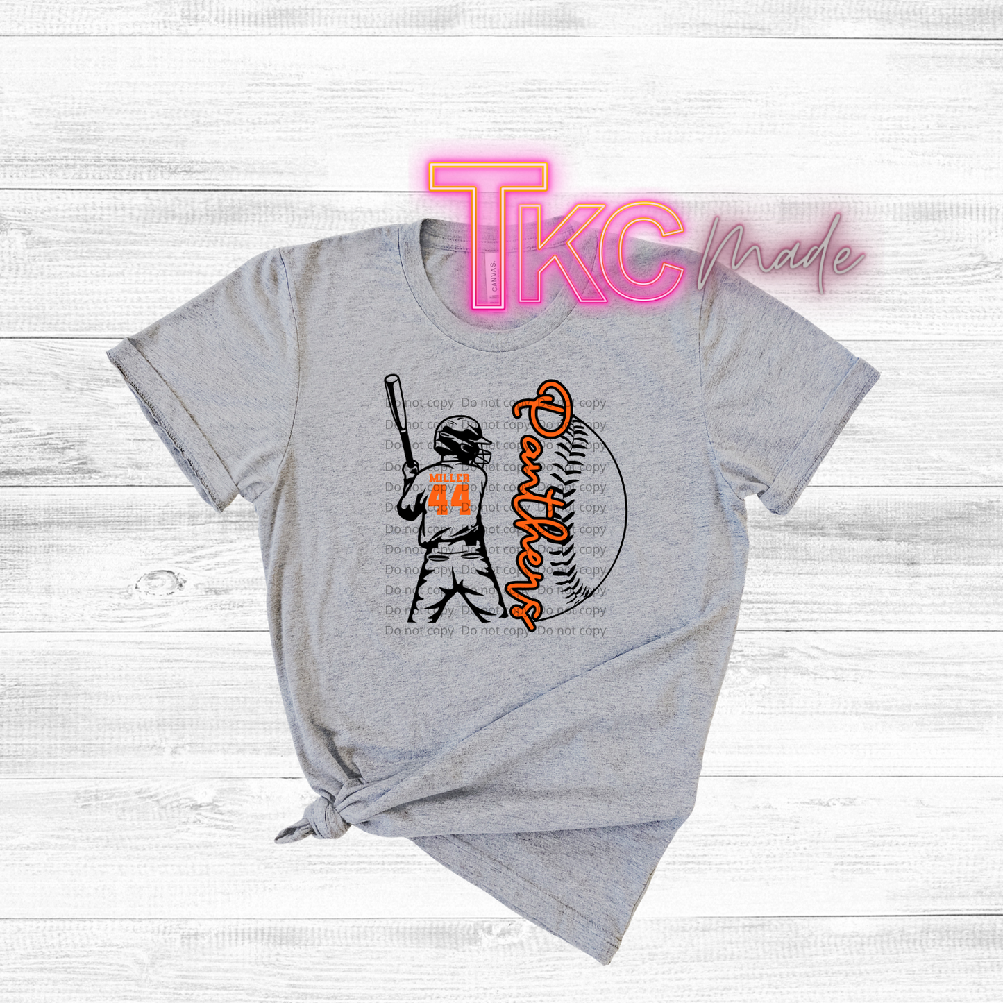 Gray t-shirt with a baseball graphic and 'TKC made' text on a wooden surface