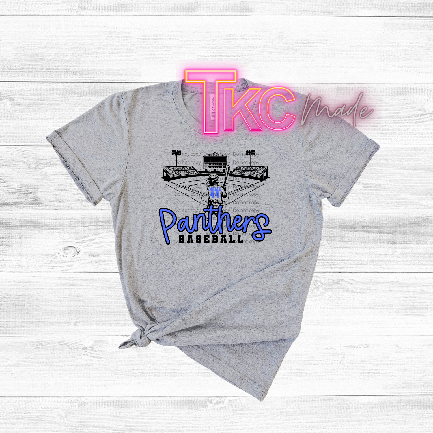 Gray t-shirt with 'Panthers Baseball' design and 'TKC' branding on a light wooden background