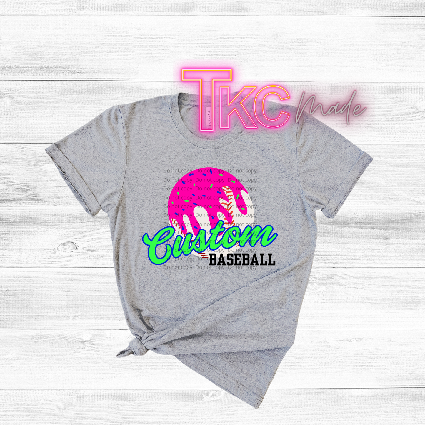 Gray t-shirt with colorful 'Custom Baseball' design and 'TKC made' text on a light wooden background
