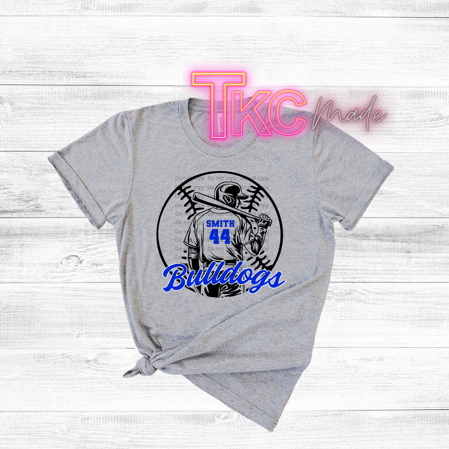 Gray t-shirt with sports-themed design and 'TKC made' branding on a light wooden background