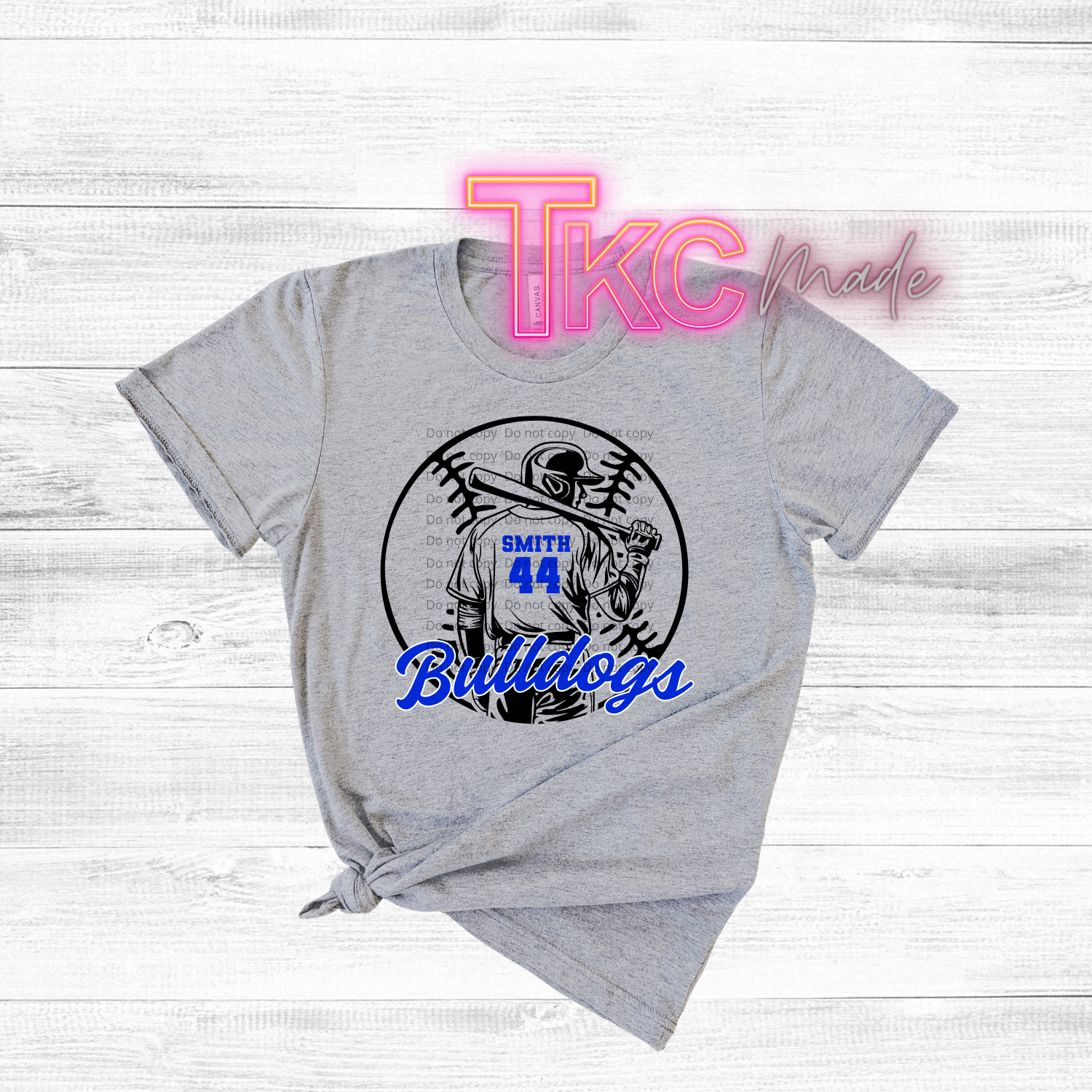 Gray t-shirt with sports-themed design and 'TKC made' branding on a light wooden background