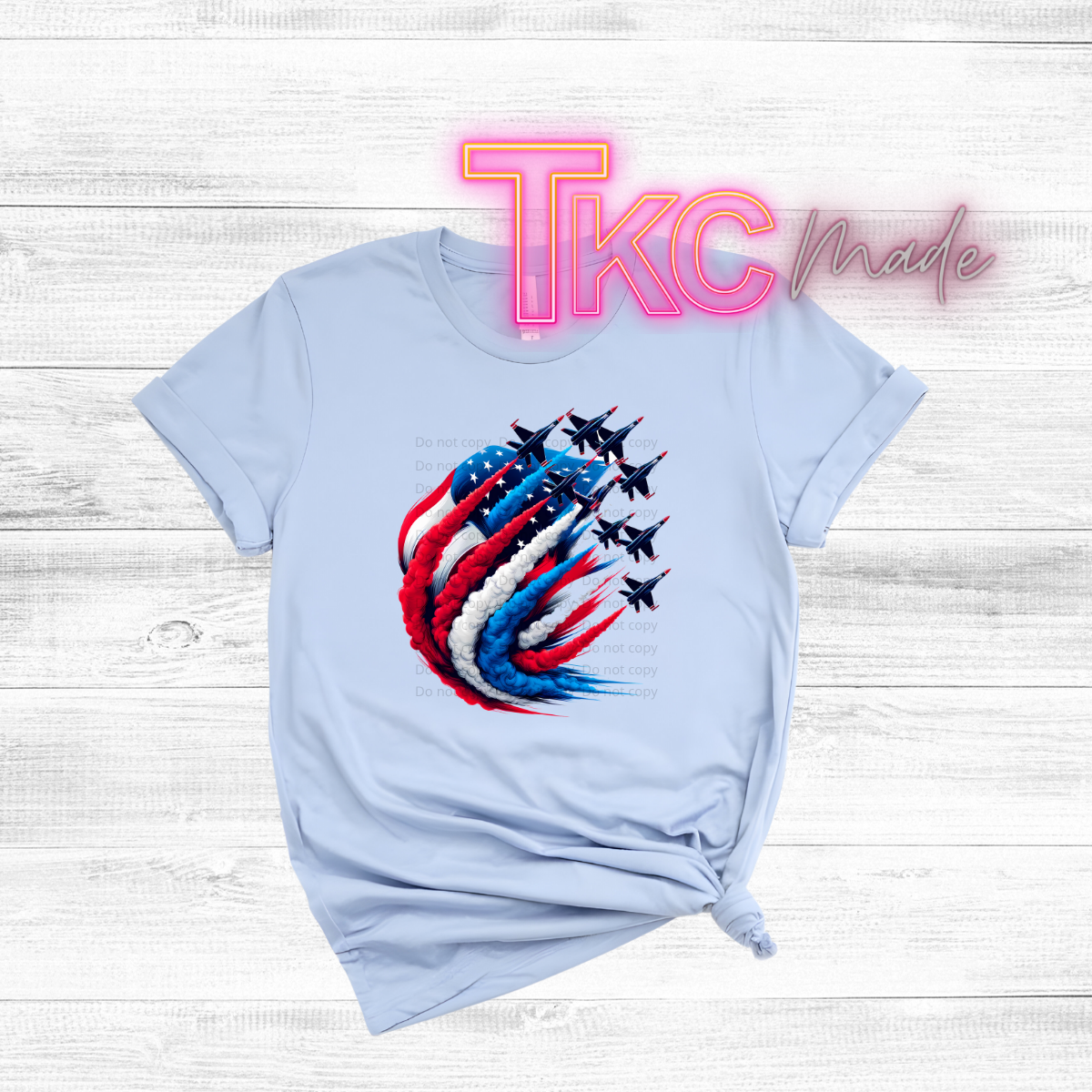Light blue t-shirt with a colorful graphic design and 'TKC Made' text on a wooden surface
