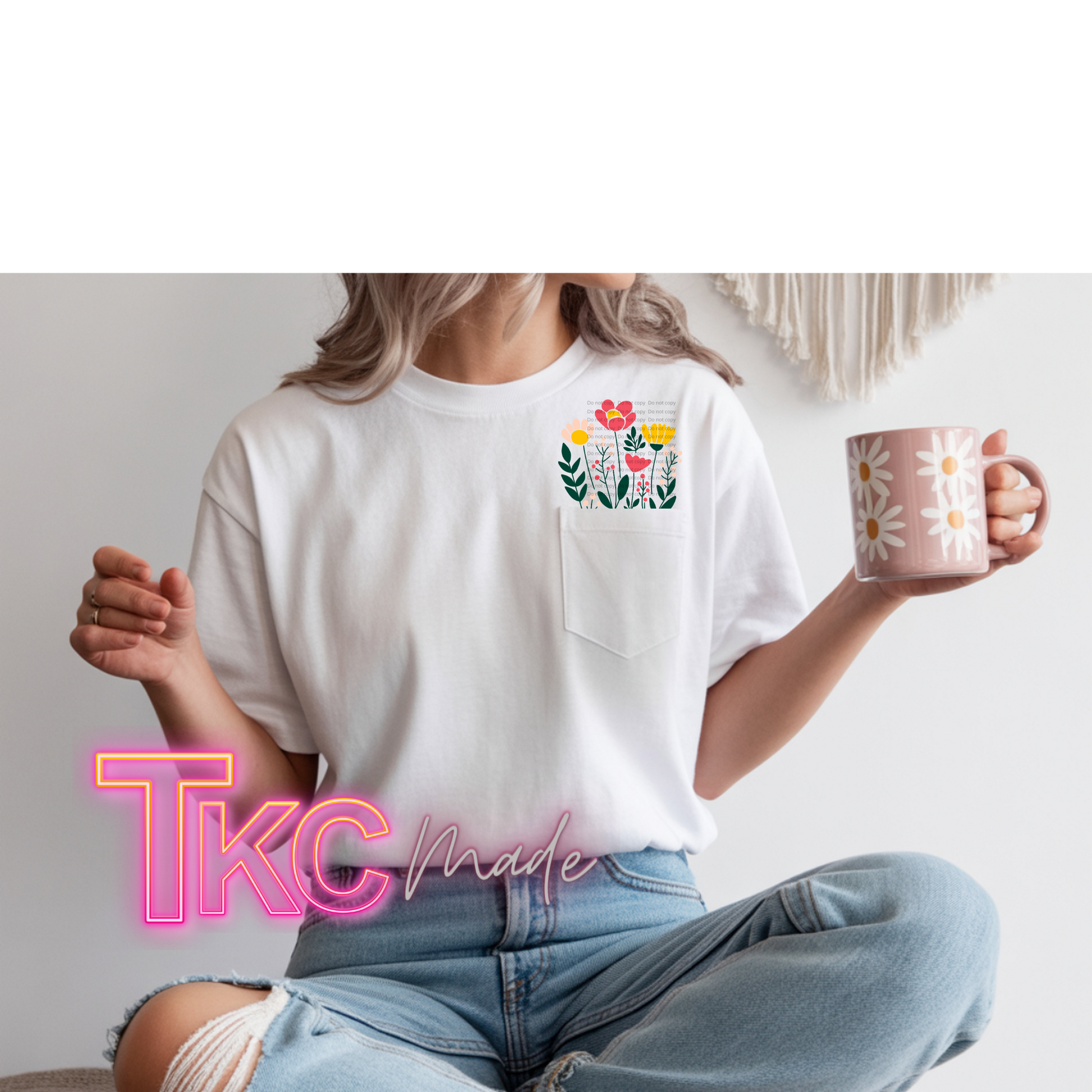 Person wearing a white t-shirt with a floral design and holding a mug, sitting on a couch.