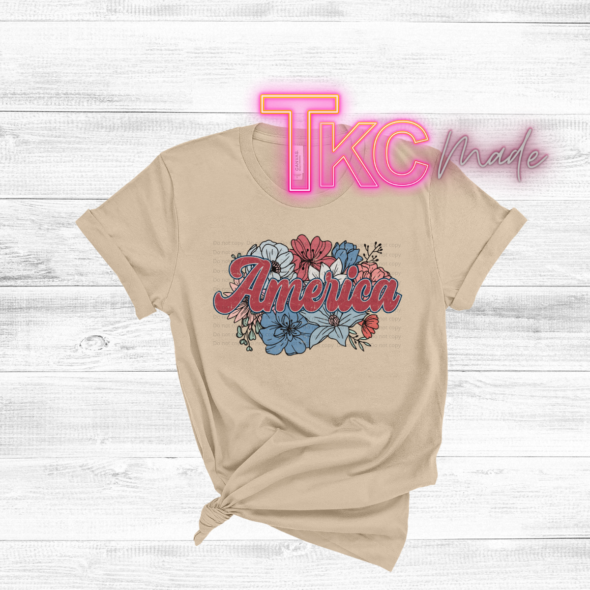 Beige t-shirt with 'America' design and 'TKC made' text on a wooden surface