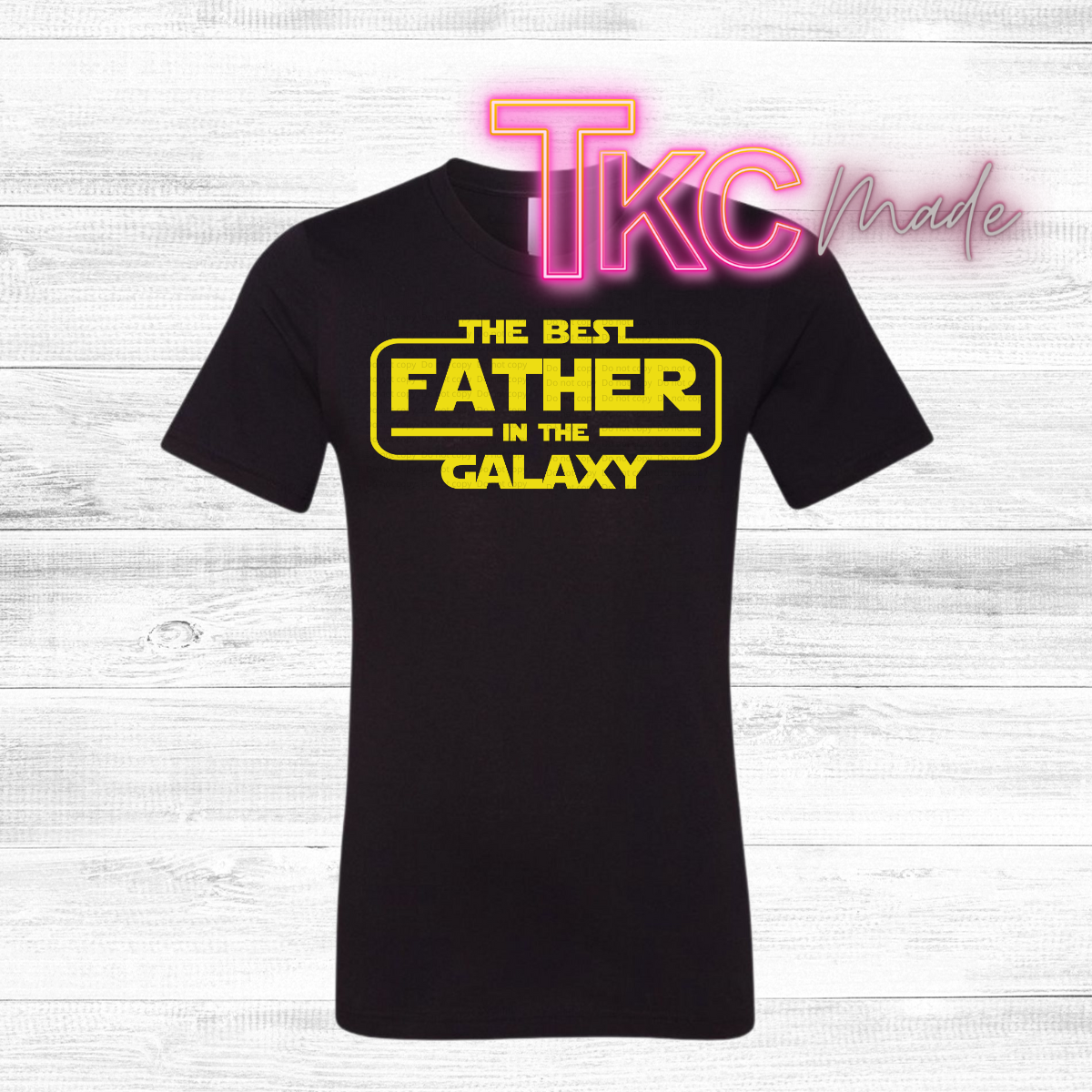 Black t-shirt with 'The Best Father in the Galaxy' text on a white wooden background