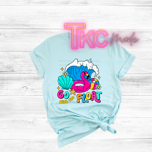 Light blue t-shirt with a colorful flamingo graphic and text on a white wooden background