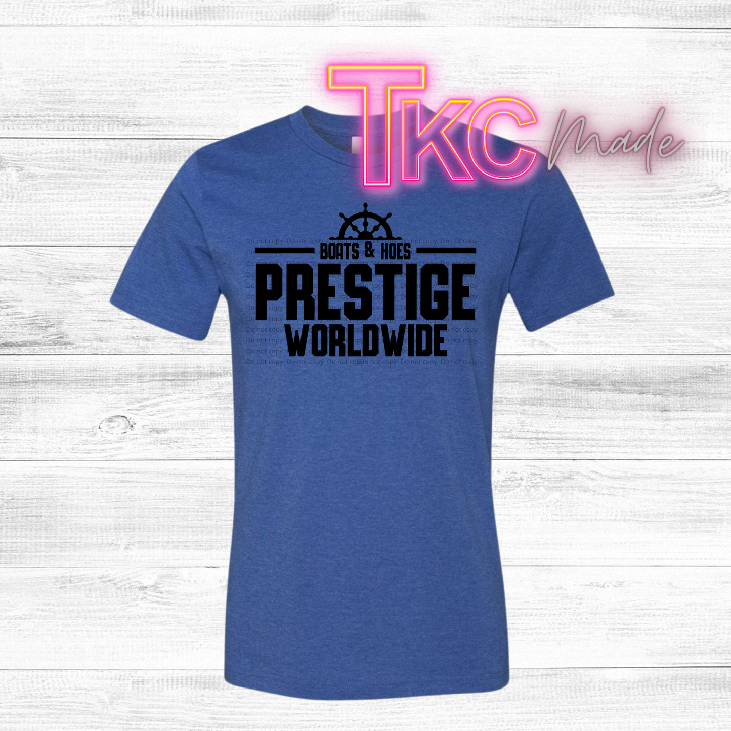 Blue t-shirt with 'PRESTIGE WORLDWIDE' text on a wooden surface with 'TKC made' branding.