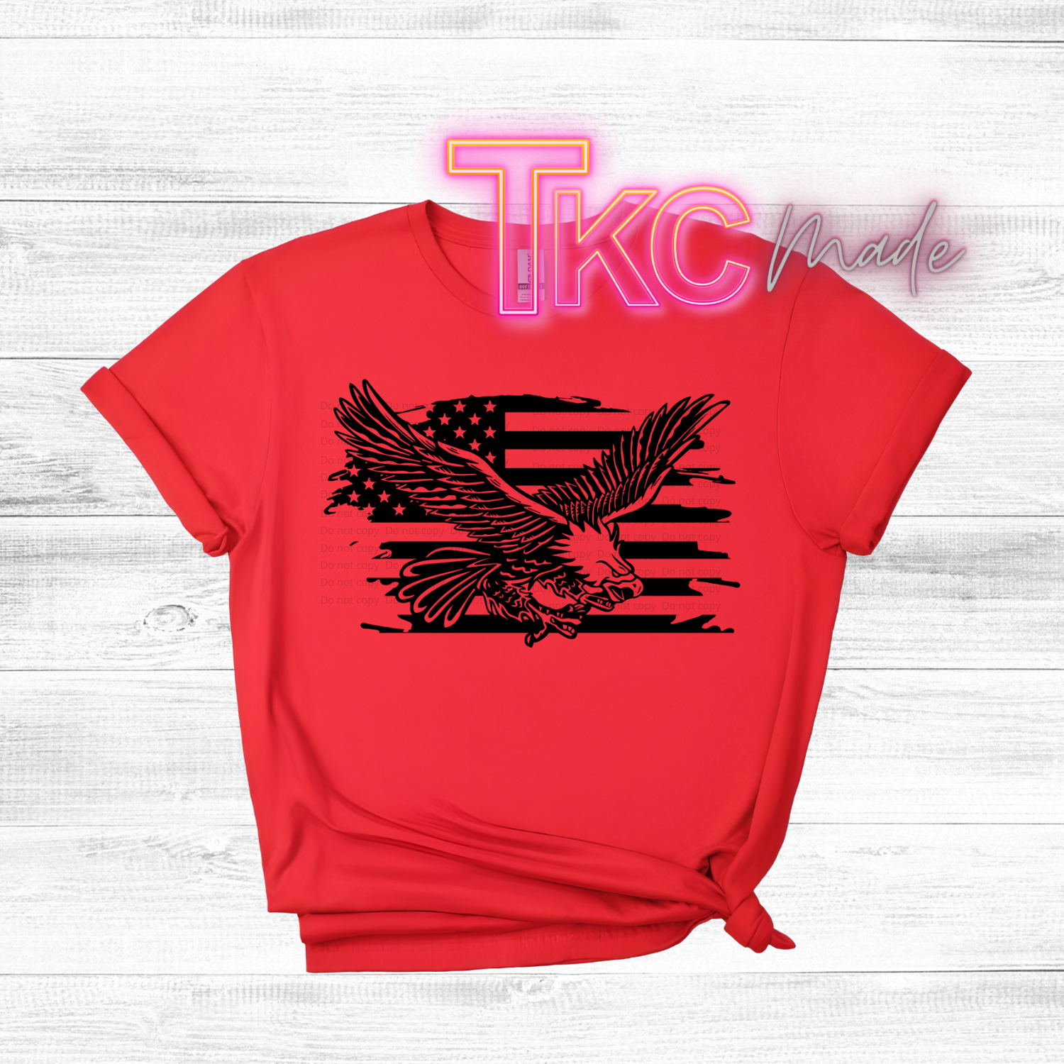 Red t-shirt with black eagle and flag design on a white wooden background, featuring 'TKC Made' text.