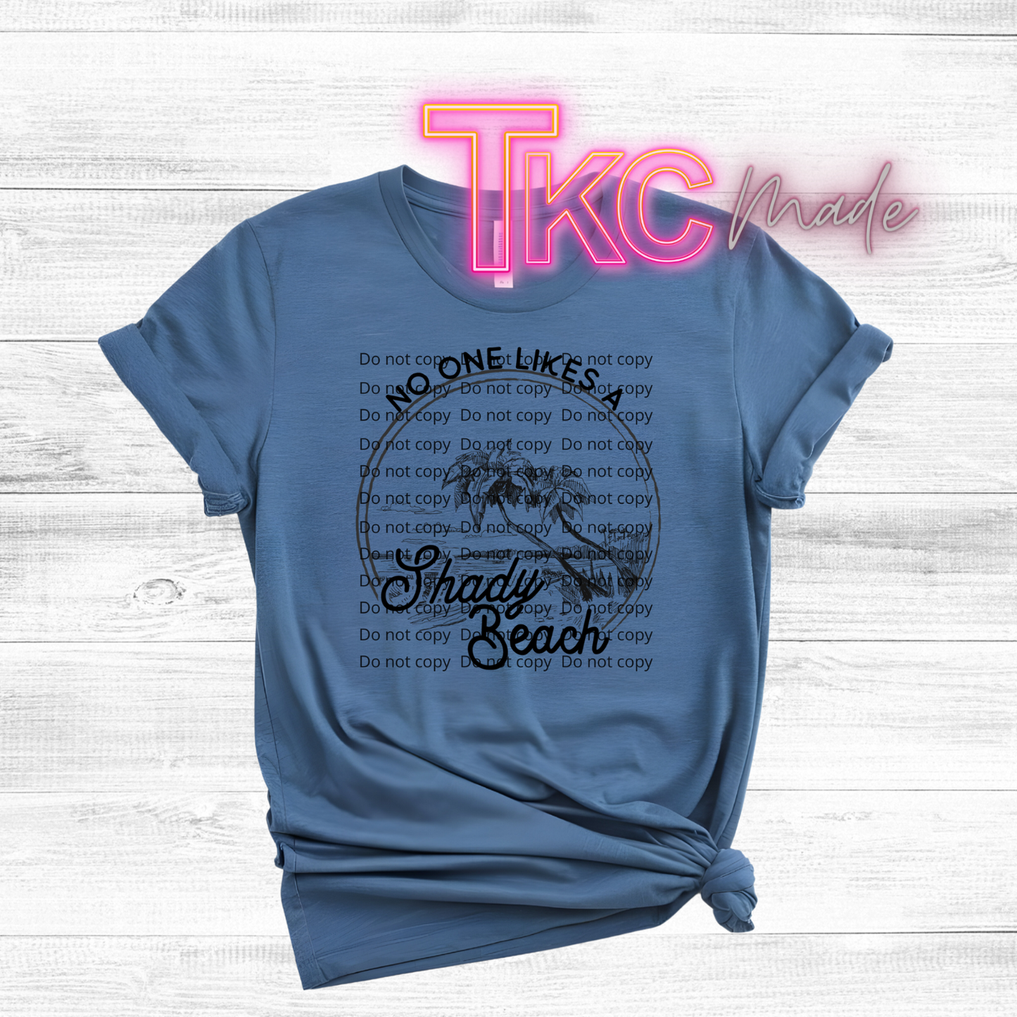 Blue t-shirt with text design reading no one likes a shady beach on a wooden surface