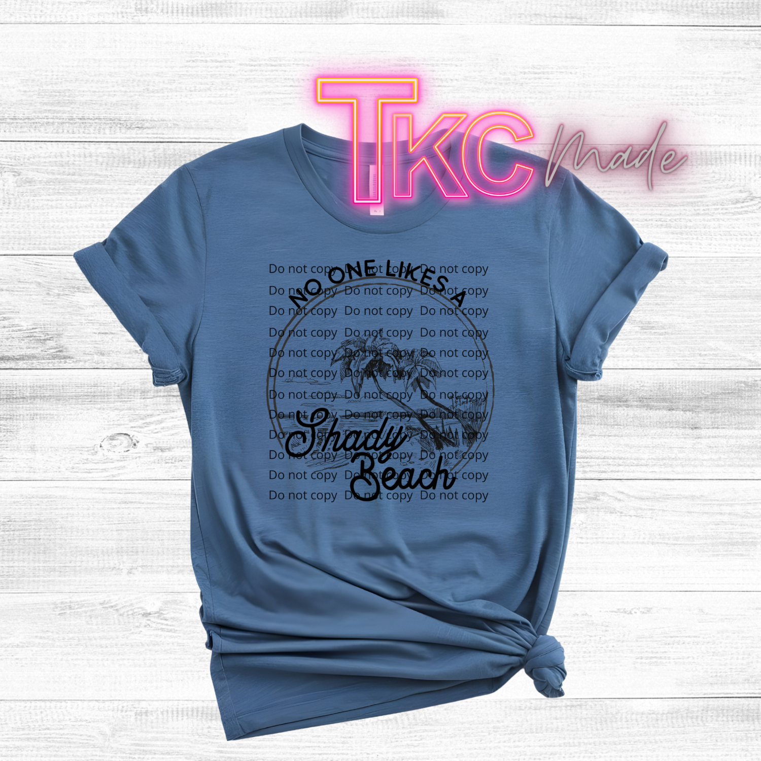 Blue t-shirt with text design reading no one likes a shady beach on a wooden surface