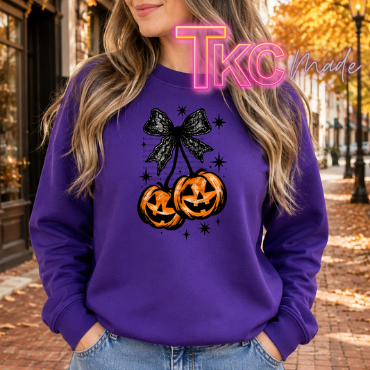 cherry with a jack o lantern pump with a black lace coquette bow on a purple sweatshirt