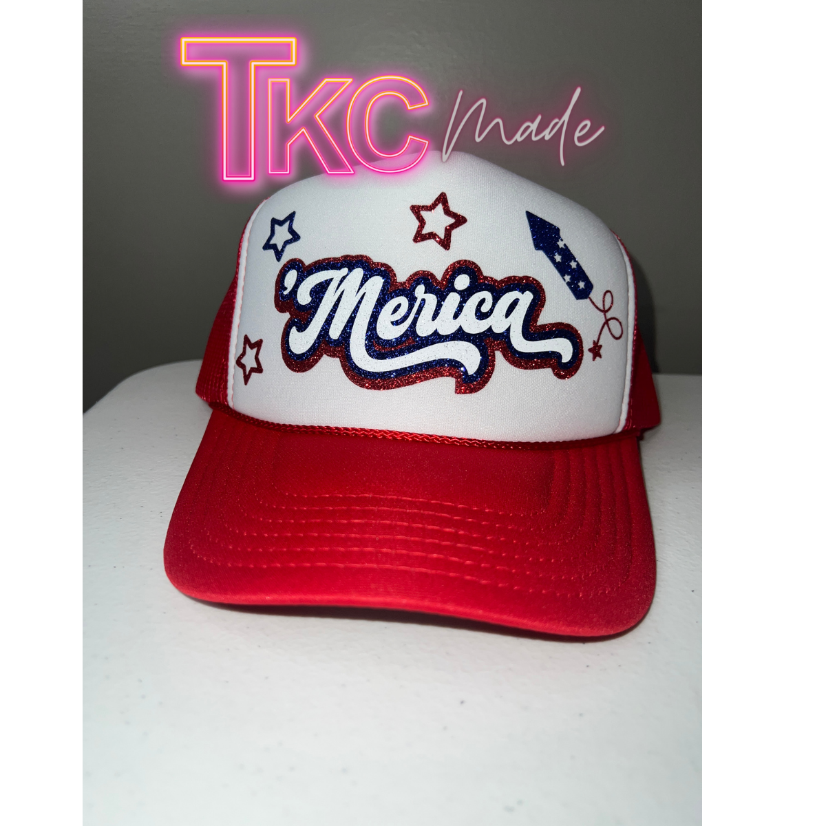 Red and white cap with 'Merica' text on a white surface, featuring 'TKC made' text in the corner.