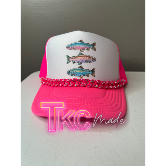 Pink and white cap with fish designs on a white surface, featuring 'TKC Made' branding.