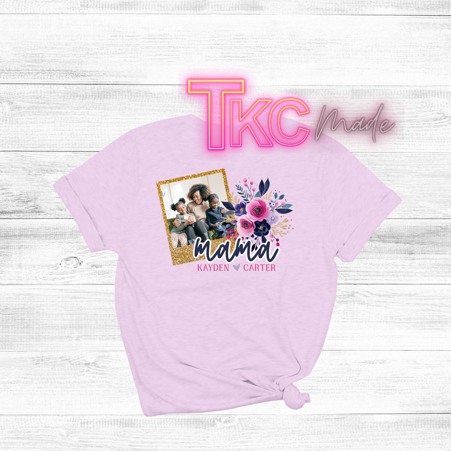 Pink t-shirt with a graphic of a family photo and floral design, on a white wooden surface.